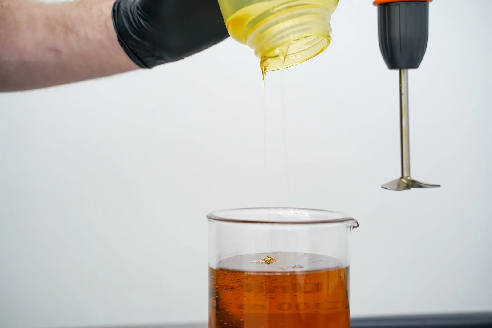 Pouring oil into a beaker with a mixer